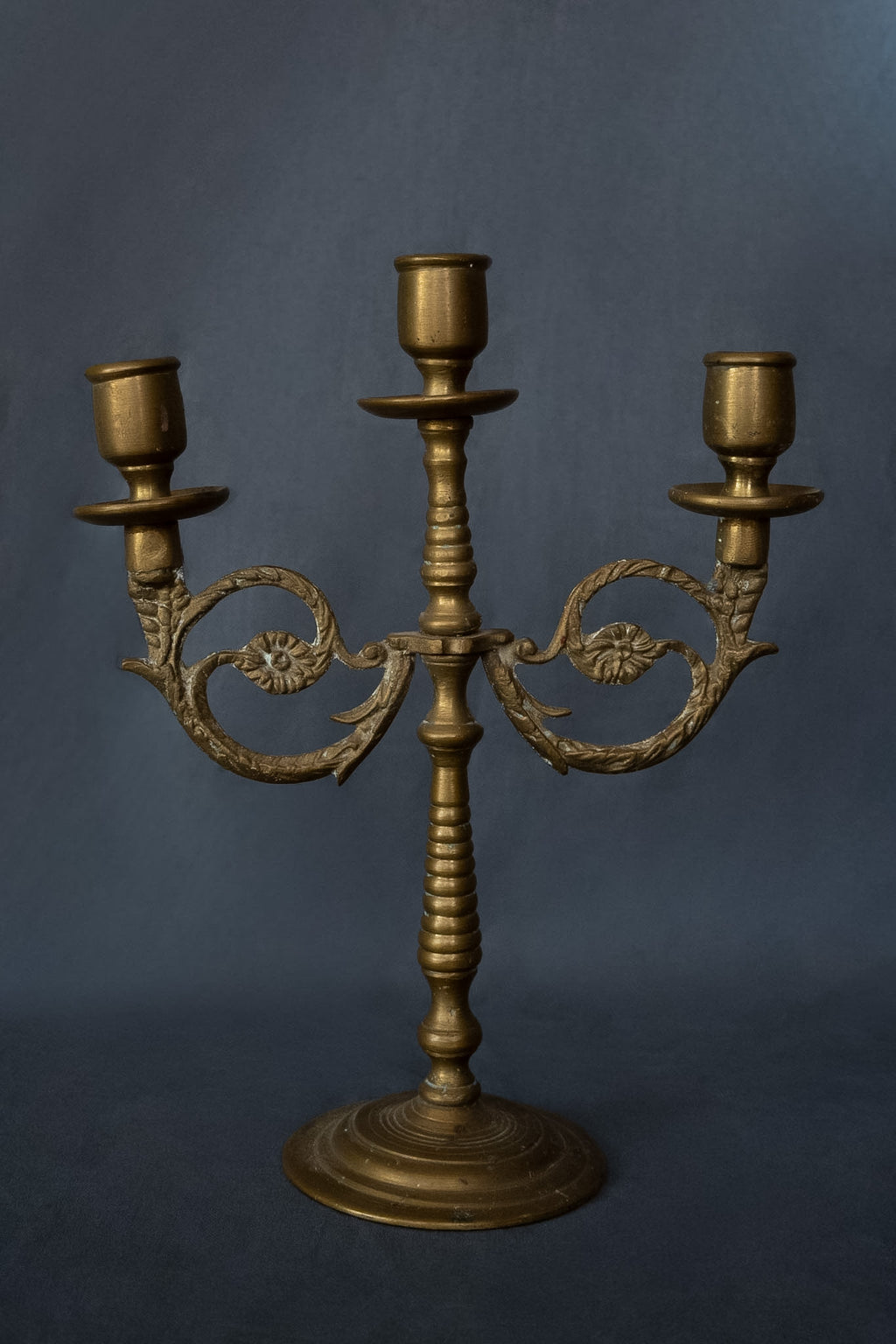 Drie-armige messing kandelaar met florale ornamenten